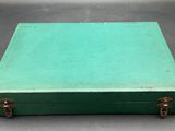 an old green suitcase sitting on top of a table