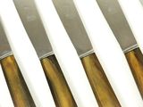 six knives are lined up in a row on a white surface