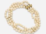 a close up of two strands of pearls with a gold clasp