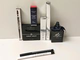 a bottle of liquid, a pen, and a box of mascaras on a table