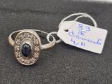 silver and gold ring with a black stone surrounded by white diamonds