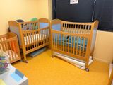 two wooden cribs in a room with yellow carpet