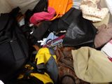 a pile of clothes and bags sitting on the floor