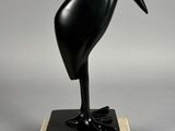 sculpture représentant un oiseau noir sur un socle en marbre, sur fond gris
