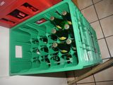 a green crate with six bottles of beer in it