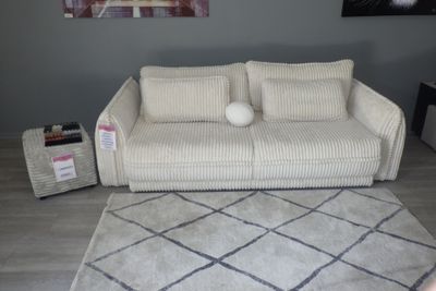 un canapé blanc placé dans un salon, à côté d'un tapis