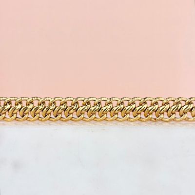 a close up of a gold chain bracelet on a pink background