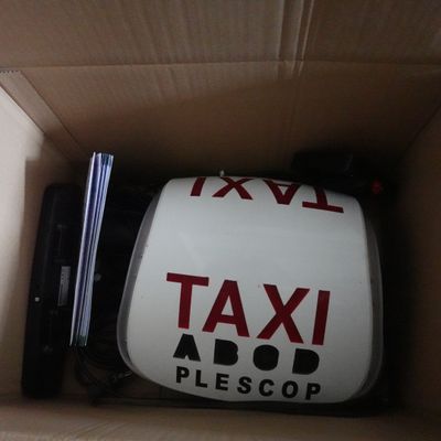 une boîte sur laquelle est apposé un panneau « taxi » et qui contient un ordinateur portable