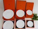 quatre assiettes blanches dans des boîtes orange, surmontées d'une plante