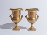 deux vases en or posés l'un à côté de l'autre sur une table