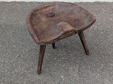 a small wooden stool sitting on the pavement