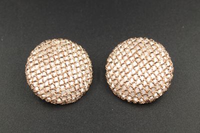 une paire de boutons en maille dorée sur un fond noir