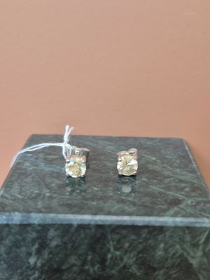 une paire de boucles d'oreilles à clous ornées de diamants jaunes, posées sur un bloc de marbre