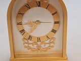 une petite horloge en or avec des chiffres romains