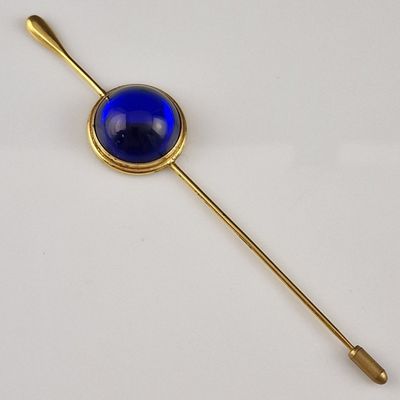 une image représentant une épingle de revers dorée et bleue posée sur une surface blanche