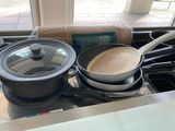 des casseroles et des poêles posées sur une cuisinière, à côté d'un rouleau de papier toilette