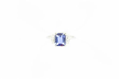 un gros plan d'une bague sertie d'une pierre bleue sur fond blanc