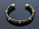 a close up of a black and gold bracelet on a table