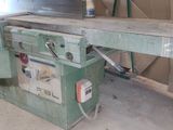 a man standing next to a table sawing a piece of wood