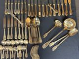 a lot of silver spoons and forks laid out on a table