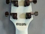 the headstock of a white electric guitar on a gray surface