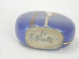 a blue stone with writing on it sitting on a white surface