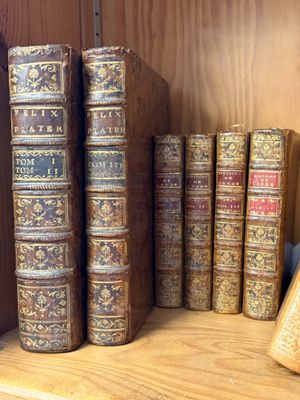 Plusieurs vieux livres sont empilés sur une étagère en bois dans une bibliothèque