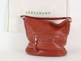 Le sac Longchamp est posé à côté d'un sac blanc et d'une serviette blanche.