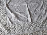 a white crocheted table cloth on a bed