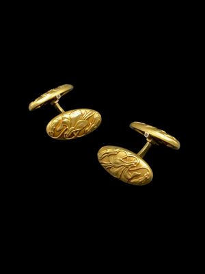 a pair of gold cufflinks on a black background