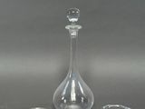 deux bougeoirs en verre et une carafe sur fond gris