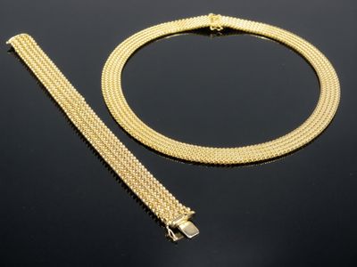 un ensemble composé d'un collier et d'un bracelet en or, posé sur un fond noir