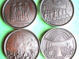 quatre pièces de monnaie sur lesquelles figurent des personnages, posées sur un fond vert