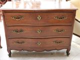 une commode en bois dans une pièce où se trouve une chaise rouge