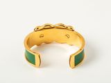 a close up of a gold and green cuff bracelet