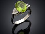 a close up of a ring with a peridot stone and diamonds
