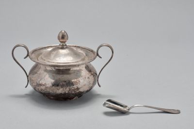 une casserole en argent posée sur une table, avec une cuillère à côté