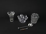 quatre verres posés sur une surface noire, accompagnés d'une cuillère et d'un repose-cuillère