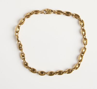 gros plan d'un bracelet en chaîne en or sur une surface blanche