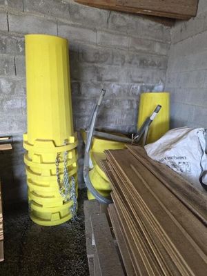 un tas de bois dans une pièce où se trouve un poteau jaune