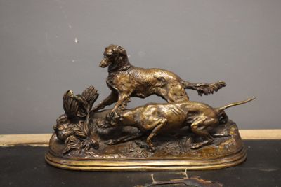 statue en bronze représentant un chien poursuivant un chat, posée sur une table