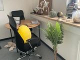 a desk with a chair and a potted plant in the corner