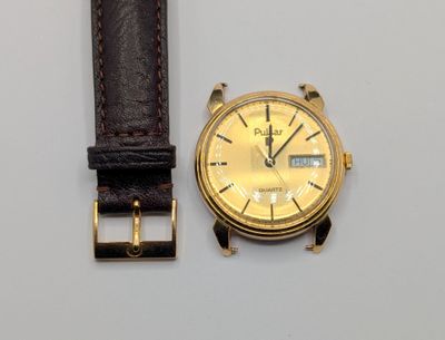 une montre en or avec un bracelet en cuir marron posée sur une surface blanche