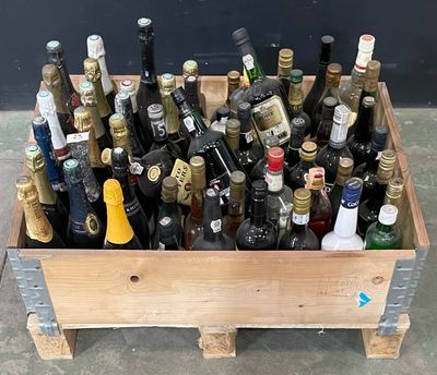 plusieurs bouteilles de vin dans une caisse en bois posée par terre