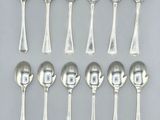 six silver spoons and two silver spoons on a white surface