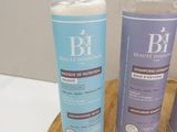 two bottles of shampooe sitting on top of a wooden cutting board