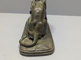 bronze statue of a dog on a cushion on a white surface