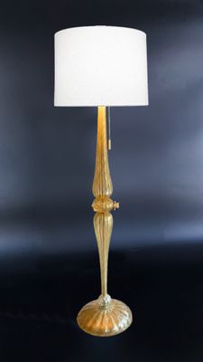 a gold table lamp with a white shade on top of it