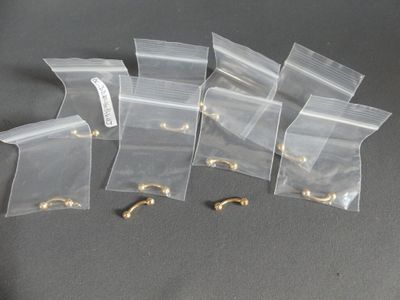 six sacs en plastique transparent munis de crochets dorés, posés sur une surface grise