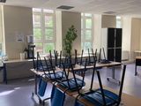 des tables et des chaises dans une salle de classe, sur lesquelles sont posés des ordinateurs portables